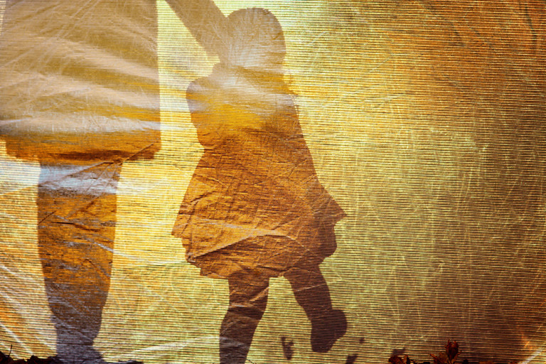 shadow of a little girl walking and holdings hands with an adult woman against a yellow background